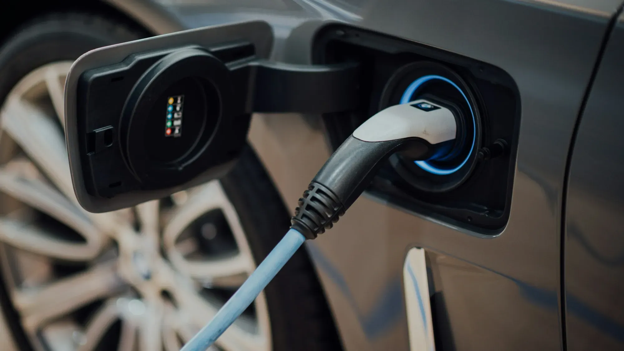 Cable de carga conectado al puerto de un carro eléctrico gris
